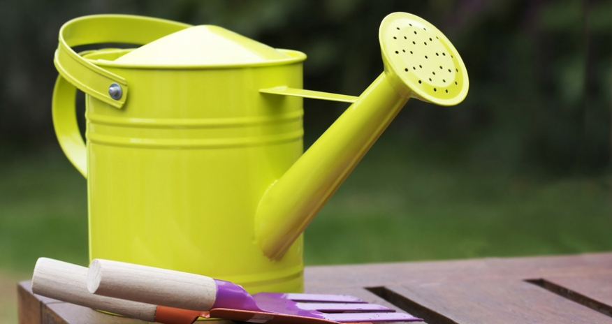 Gradening Program for Kids watering can and gardening tools on a table outdoors