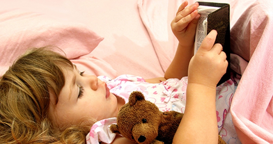 Snuggle Up and Read Storytime a photo of a girl reading in bed with a teddy bear