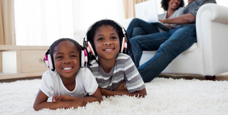 OverDrive Kids Little boy and girl lying on a carpet listening to headphones