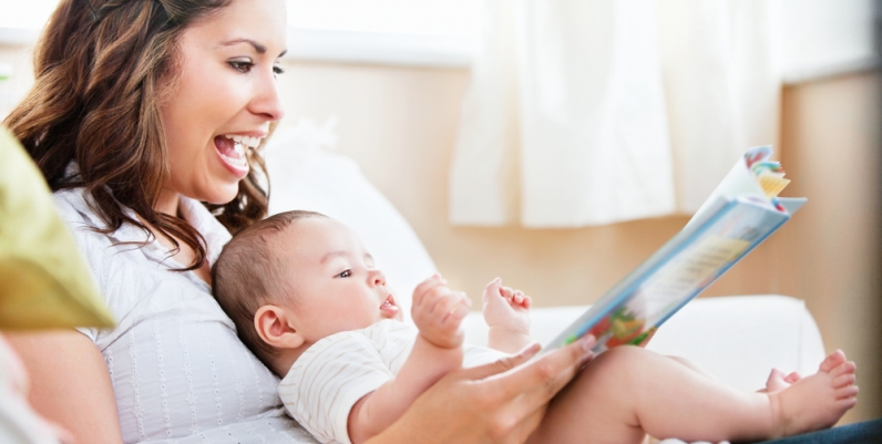 Mother reading a book to her baby that is sitting in her lap