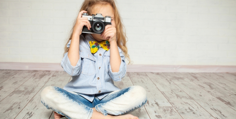 kid_photography a photo of a girl with a camera sitting on the floor