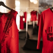 Two red dresses in focus with tire marks and handprints on them.