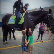 two boys speaking with a cop on a horse 