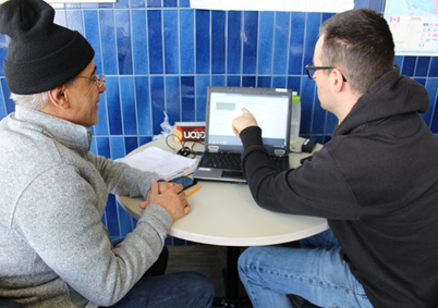 Two individuals sat at a table with a laptop computer partaking in tutoring